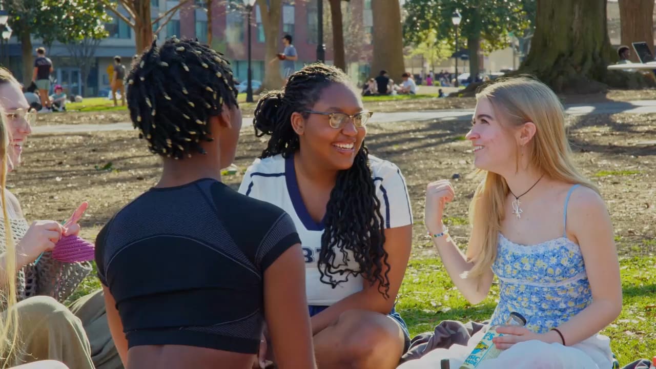 A diverse group of five students enjoying a beautiful sunny day while sitting down and chatting in VCU's Monroe Park 